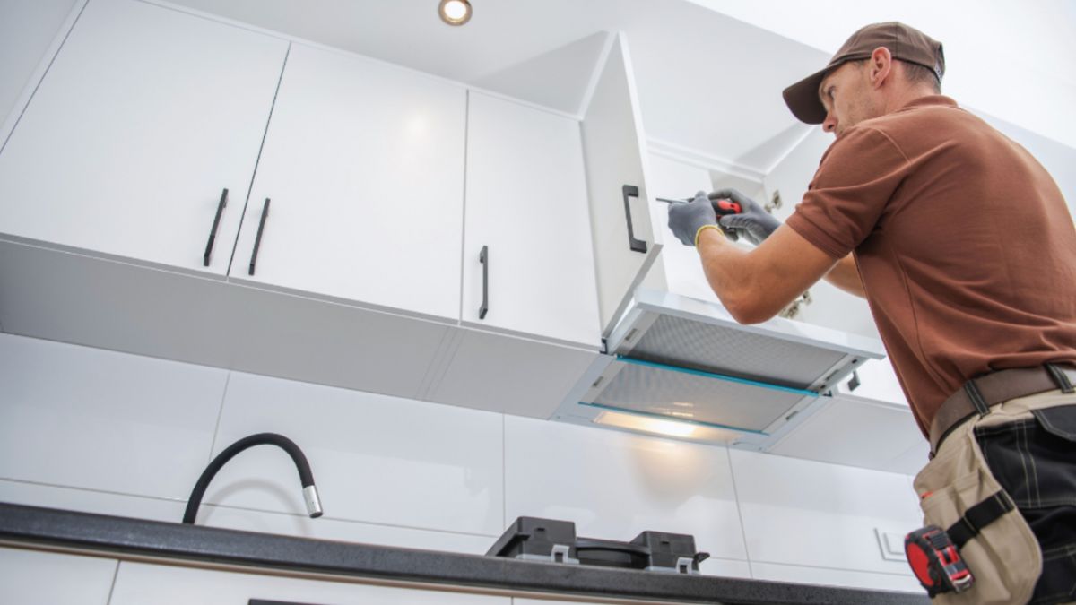 A man works on a kitchen cabinet, showing the work involved in kitchen remodeling projects.