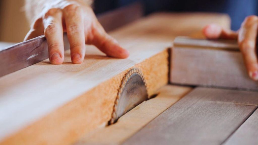 A craftsman uses a saw to cut wood in a wood shop, showcasing the detailed and precise woodworking involved in custom projects.