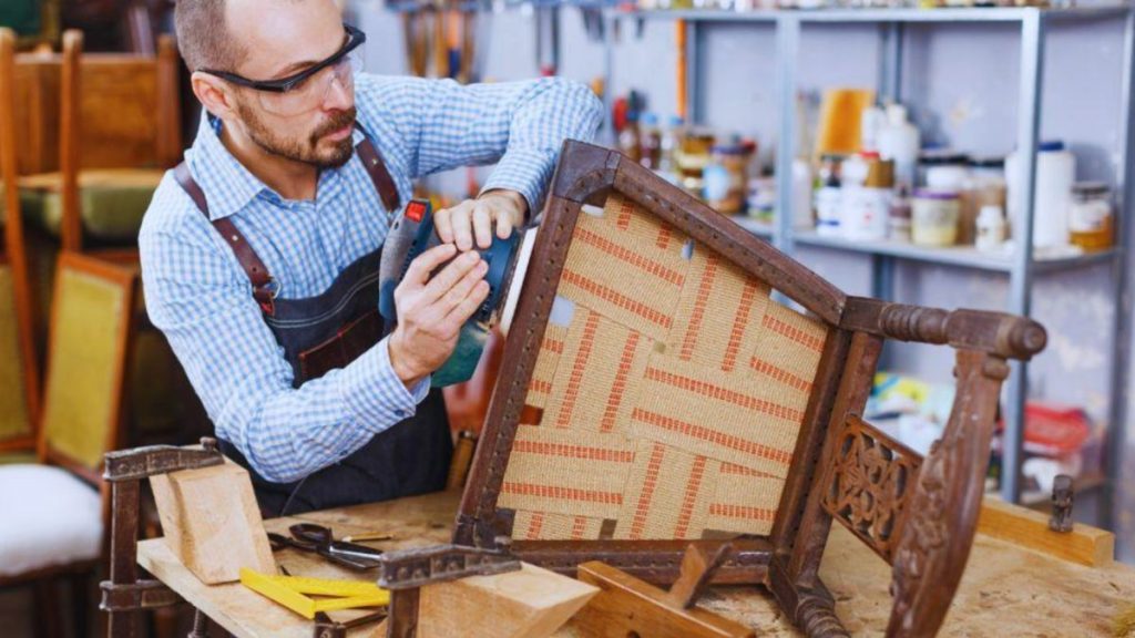 Close-up of a craftsman repairing a chair in a wood shop, highlighting the meticulous work of wood furniture restoration.